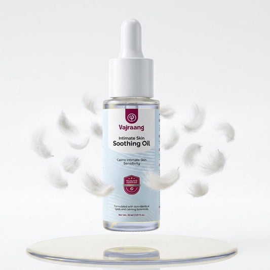 Vajraang Intimate Skin Soothing Oil bottle on a white background with droplets around it.